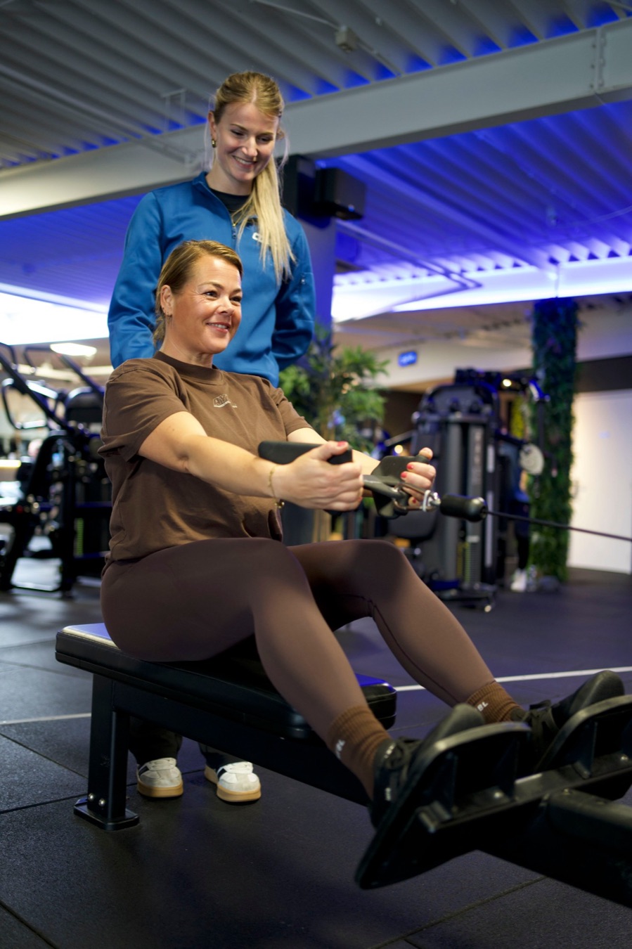 Een coach van UltraGym Hardenberg kijkt mee naar de techniek van een lid bij een roeioefening aan de kabel