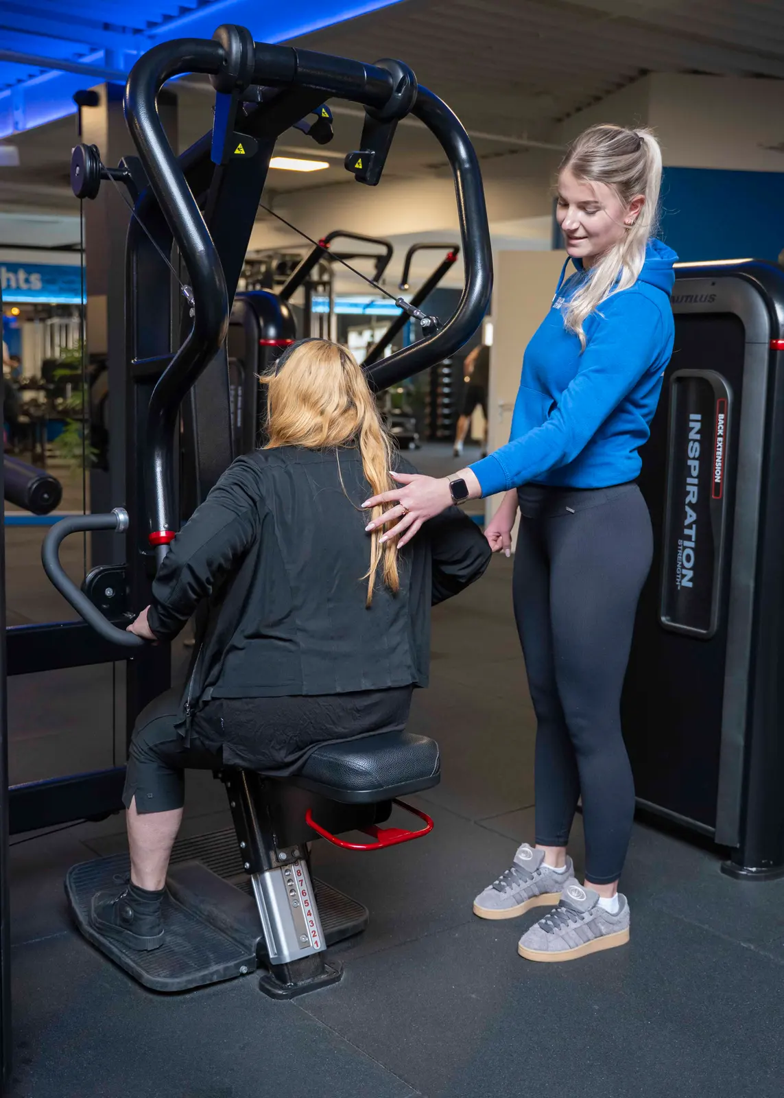 Trainer legt een nieuw lid een apparaat uit bij UltraGym Hardenberg