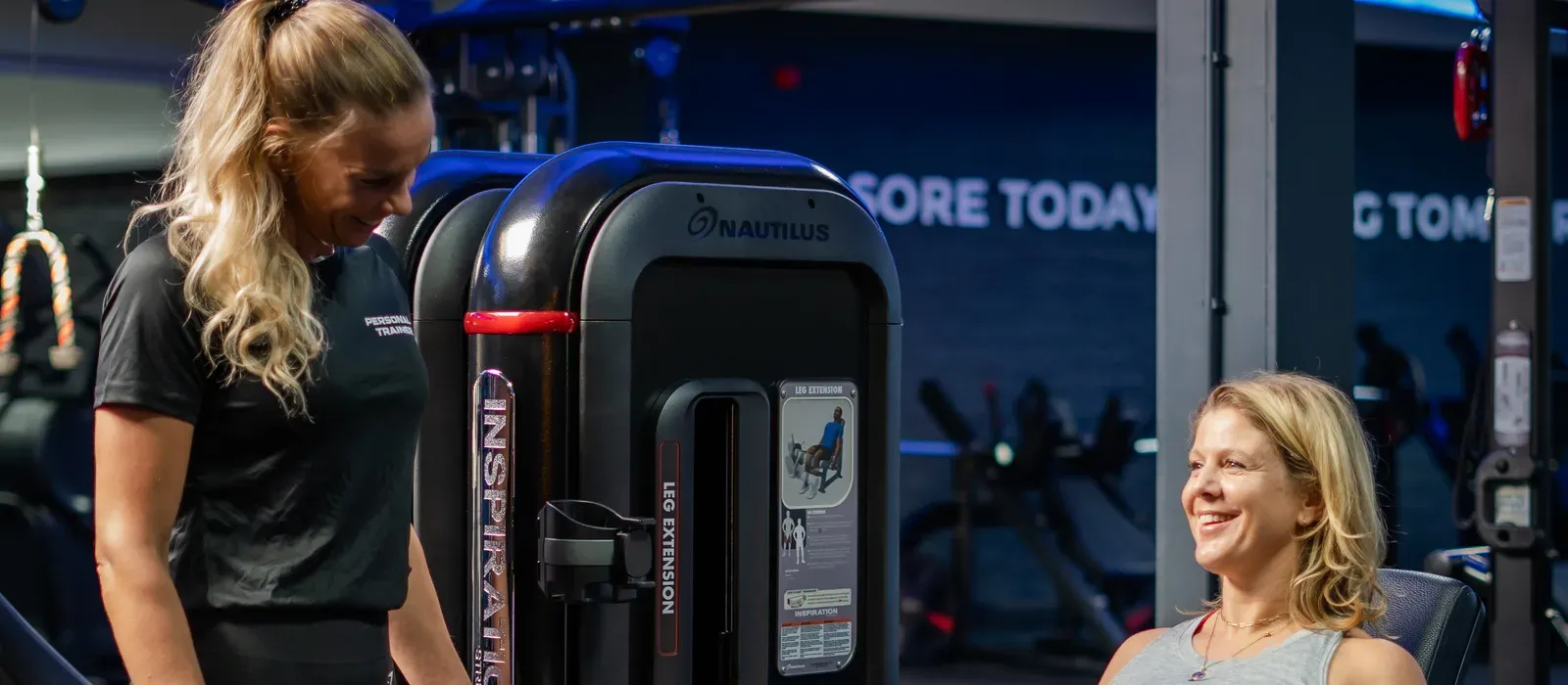 Personal trainer begeleidt een lid op de leg extension bij UltraGym